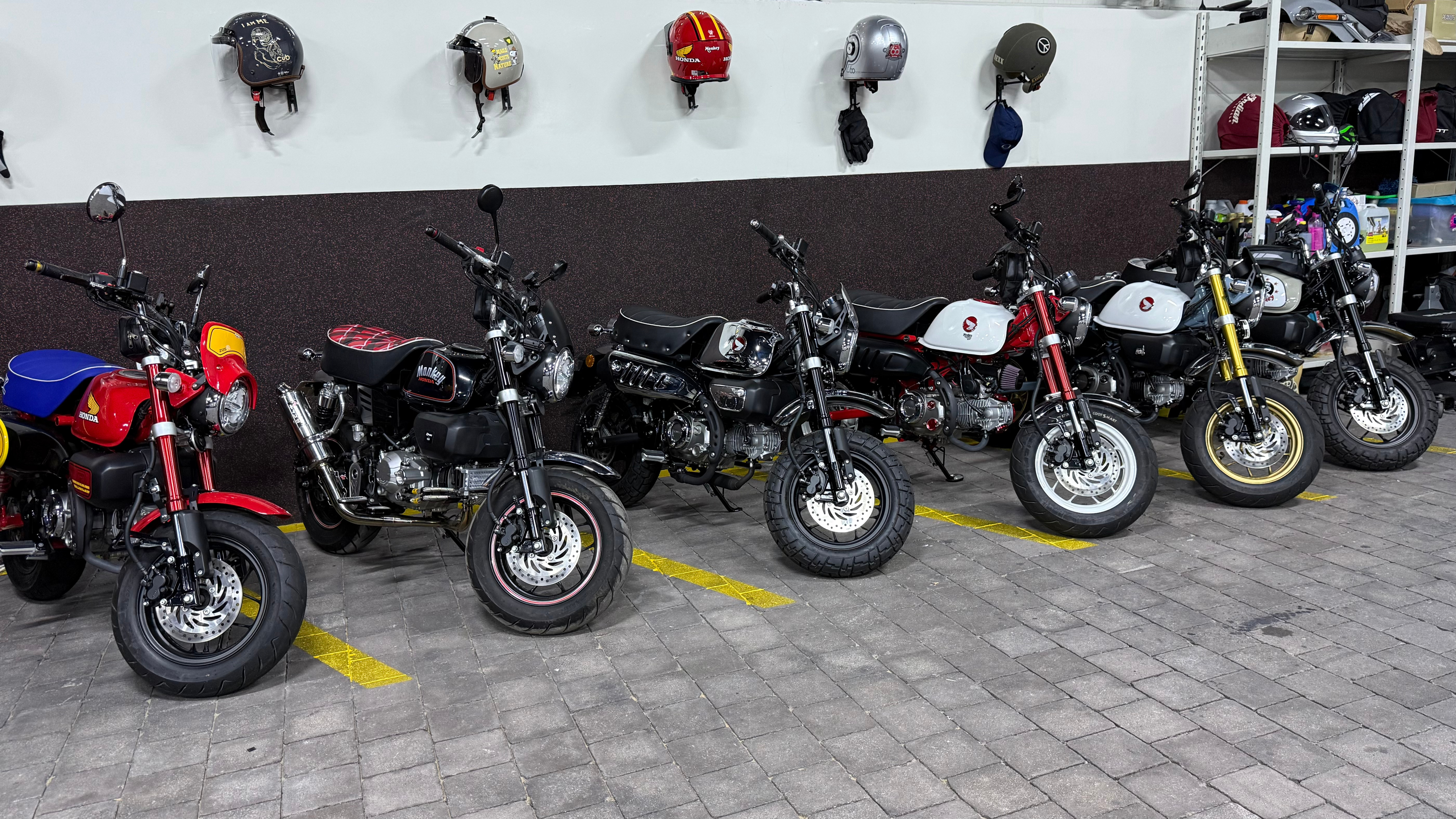 Multiple Honda Monkey Bikes parked in a secure indoor storage facility with helmets on the wall, part of Motocare’s dedicated Monkey Bike storage service in Dubai