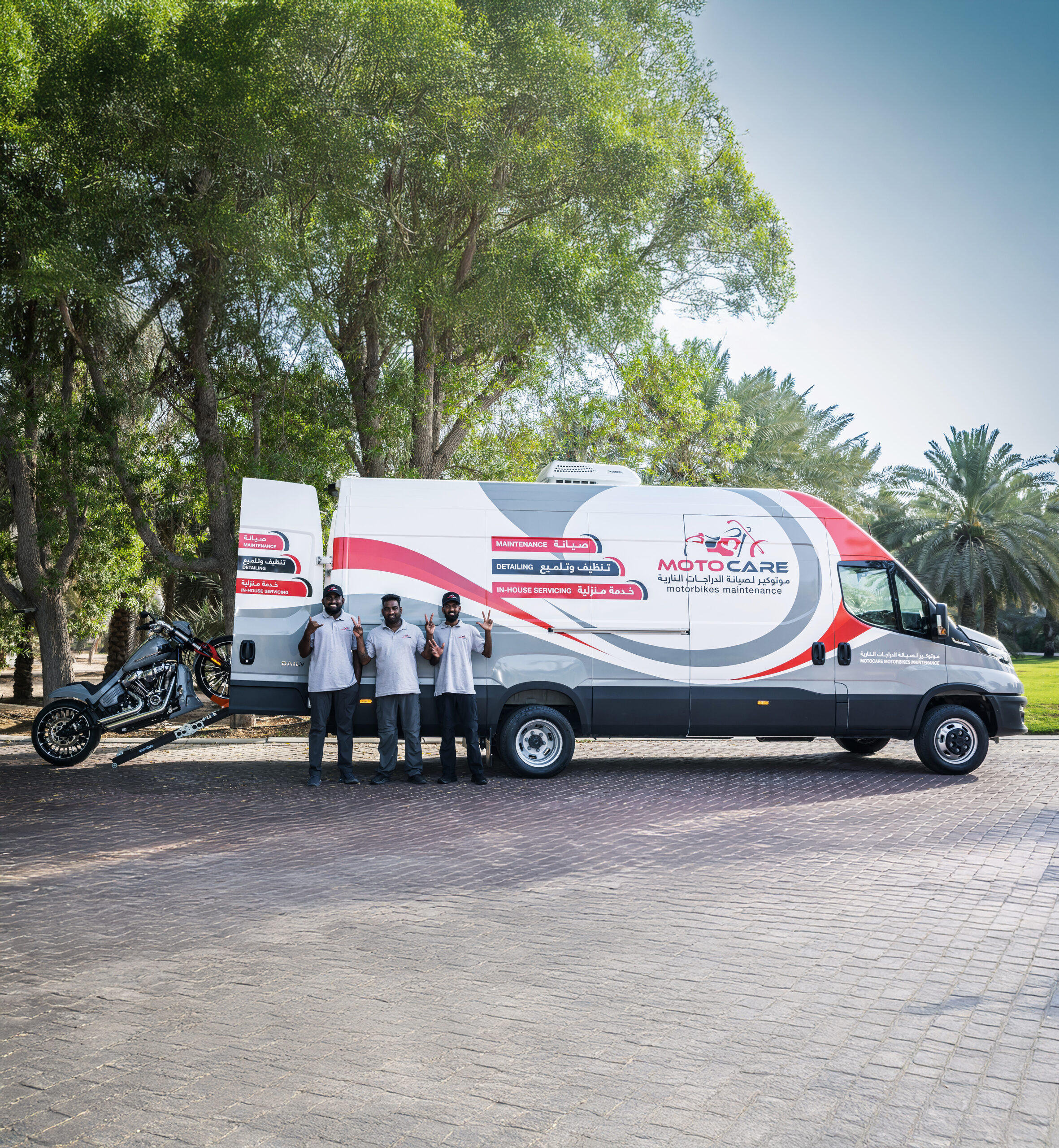 Moto Care mobile motorbike maintenance van with staff and motorcycle ramp in outdoor setting